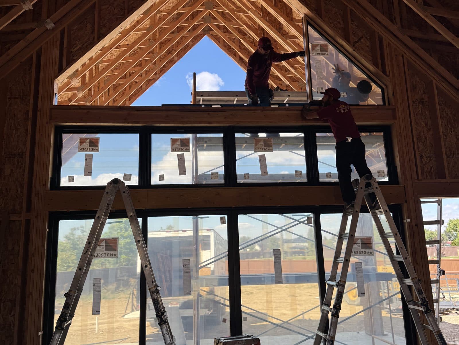 Wood Windows installers setting an Andersen window wall in a vaulted new build