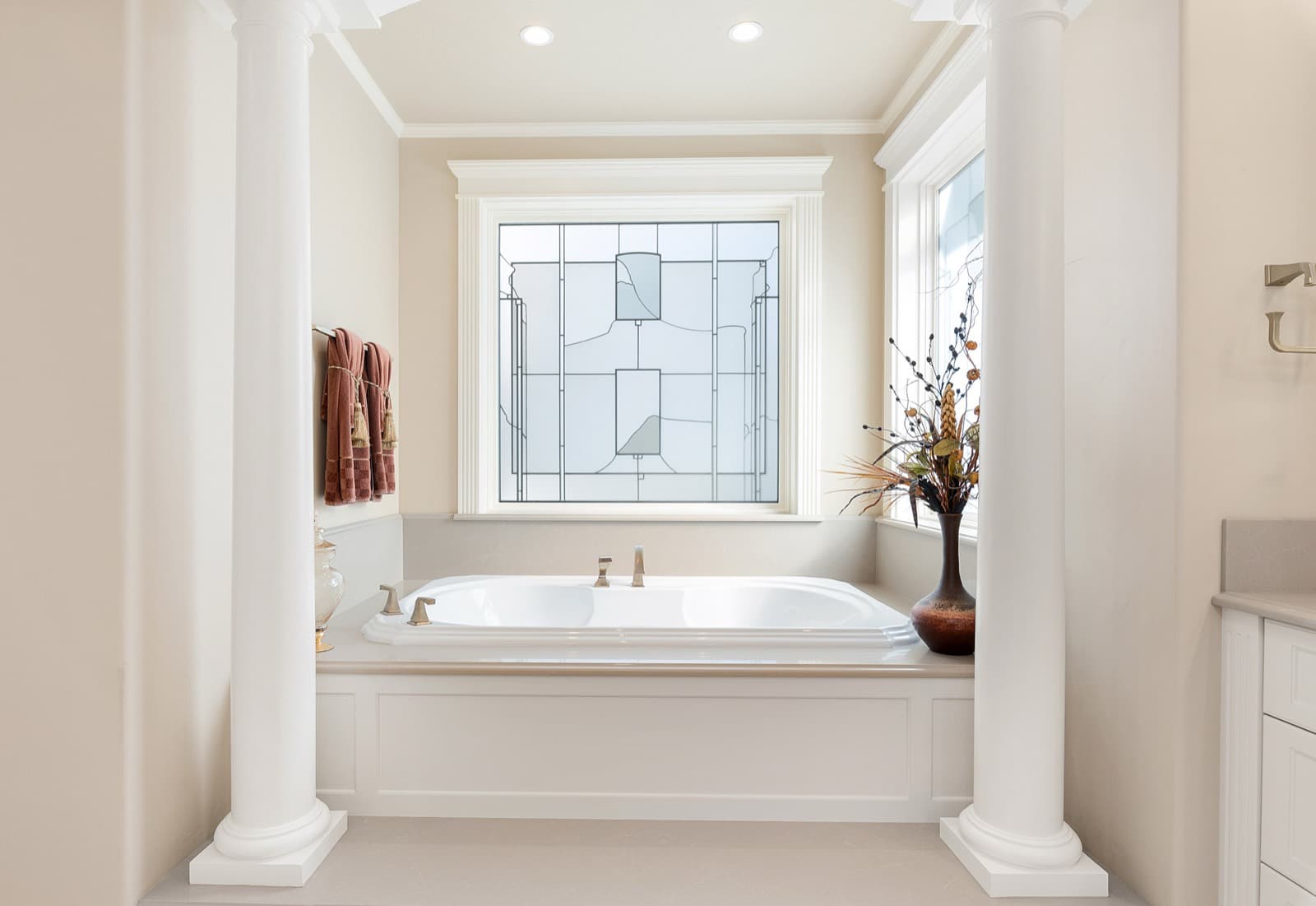 Primary bathroom with a soaking tub, columns and a leaded-glass window